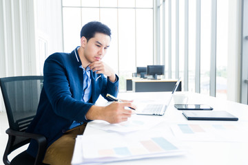asian young businessman have ideas make a note business plan of notebook and laptop computer on wooden table background in office.