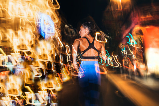 Woman running in the city with flashing lights at night