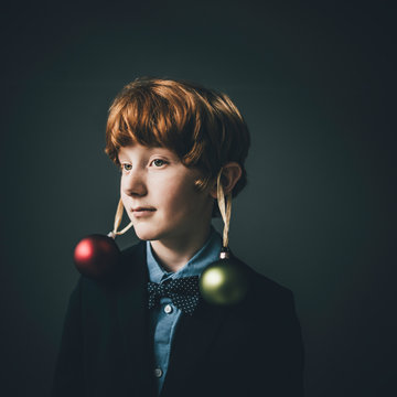 Portrait of redheaded boy wearing bow tie and Christmas baubles