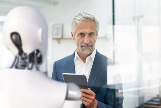 Businessman using digital device to control robot