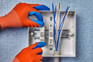 A handyman installs the fuse box in home wiring.