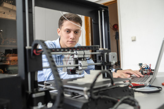 Student setting up 3D printer, using laptop