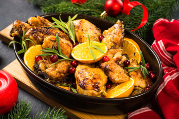Christmas food - roasted chicken with orange on dark table.