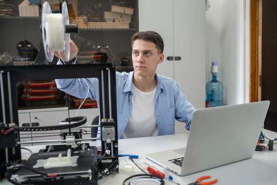 Student setting up 3D printer, using laptop