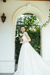Fototapeta premium Beautiful bride with wedding flowers bouquet, attractive woman in wedding dress. Happy newlywed woman. Bride with wedding makeup and hairstyle. Smiling bride. Wedding day. Gorgeous bride. Marriage.