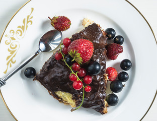 Chocolate biscuit cake with fresh berries on the white plate top view