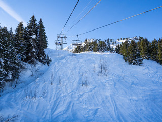 France. january, 2018: Ski lift and ski slope with skiers under it on sunny winter day with blue sky. Alpine resort Meribel, Europe