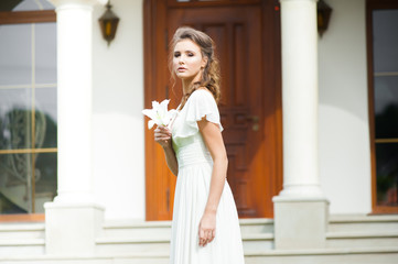 Beautiful young woman walking in long white dress. Tender bride with wedding bouquet.