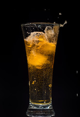 Glass of beer with foam on a black background in the dark