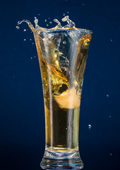 Full narrow glass of beer with foam on a blue background
