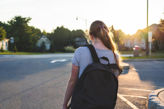 Teen Girl Depressed/sad At Sunset In A Parking Lot While Wearing A Backpack And Holding Binders.