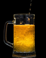 Glass of beer with foam on a black background in the dark