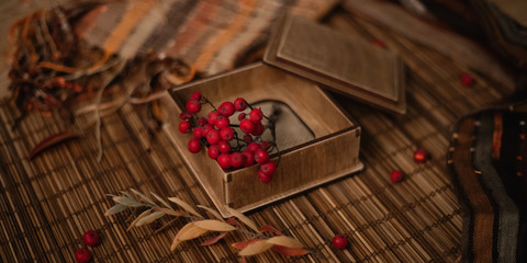 Gift, autumn leaves and berries on wooden background