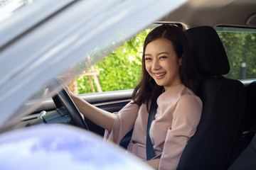 Happy Asian women driving a car and smile with glad positive expression during the drive to work office in workday