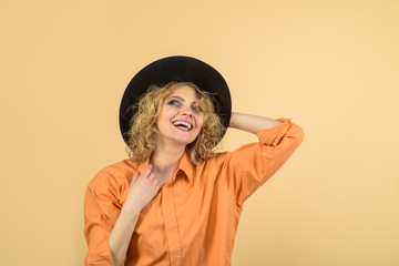Happy girl in black hat. Beauty, fashion, female accessories. Female autumn fashion. Fashionable woman in hat and orange shirt. Stylish sexy blonde model in black hat. Sexy girl with bright makeup.