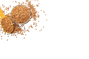 Buckwheat in a glass bowl with a wooden spoon, buckwheat groats on a white background.