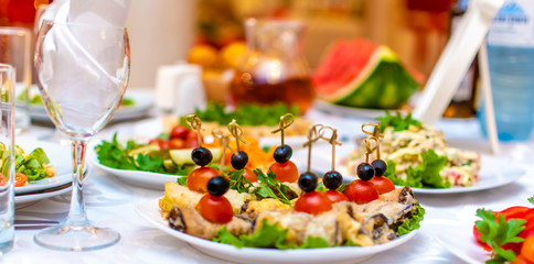 Wedding. Event. Banquet. Catering. Sandwiches snack.Decorated festive table with plates and glasses. Decanters with Morse red.