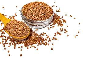 Buckwheat in a glass bowl with a wooden spoon, buckwheat groats on a white background.
