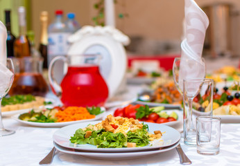 Wedding. Event. Banquet. Decorated festive table with plates and glasses, beautiful white napkins. A plate of grapes, apples and peaches. Decanters with Morse red.