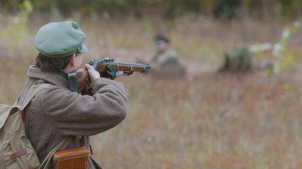 A military man is ready to shoot right on the field near other soldiers