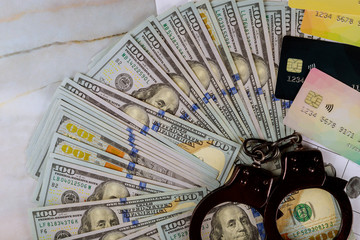 Handcuffs, US dollar banknotes cash credit cards on of cyber crime online fraud