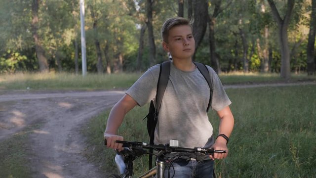 Teenage boy rides bike in city park at sunny day. Healthy lifestyle concept.