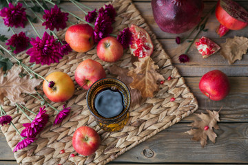 Glass of red wine, apples, grapefruits, autumn leaves and flowers on a wooden table