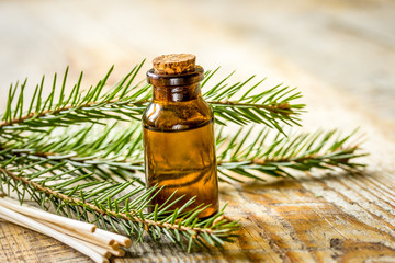 Bottles of essential oil and fir branches for aromatherapy and spa on wooden table background