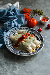 Papadzules traditional dish from the Yucatán Peninsula -  corn tortillas dipped in a sauce of pumpkin seeds filled with boiled eggs, garnished with a cooked tomato-pepper sauce