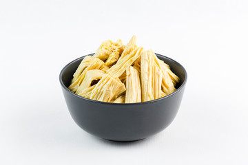 Korean marinated asparagus in a black bowl on a white background, isolate, close-up side view.