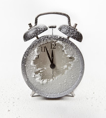 Snow-covered alarm clock. It's five minutes to midnight.
