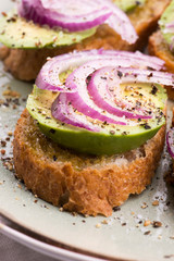 Sandwich with fresh avocado and onion on a plate