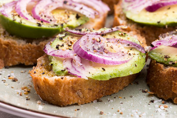 Sandwich with fresh avocado and onion on a plate