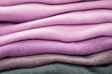 Warm clothing neatly folded on a store shelf. Sweatshirts, sweaters, jumpers, cardigans, hoodies, bobmers with piles on the shelf. Clothes storage. Size range.