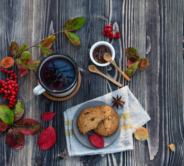red cup of tea with cinnamon stick, jam and cookies on wooden table autumn mood