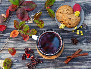 red cup of tea with cinnamon stick, jam and cookies on wooden table autumn mood