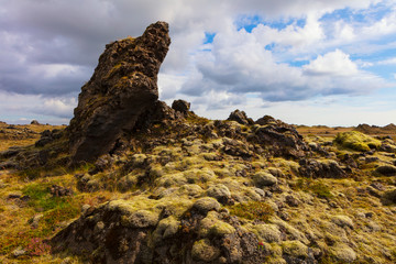 A cloudy sky and the ancient lava field, covered with moss near Vik, Iceland, seen from the famous Ring Road that is well traveled by tourists.