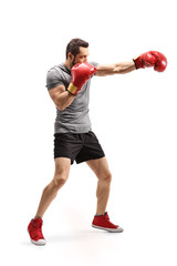 Strong young man punching with boxing gloves
