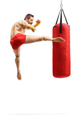 Man exercising kickbox and punching a bag with leg