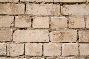 Old, beginning to collapse, carelessly laid brickwork, made of white brick. Background.