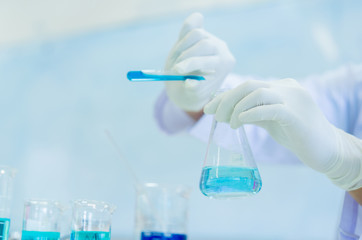 close up asian scientist man wear protective glove holding test tube flask and  blending scientific liquid solution to beaker at laboratory room for research and development about medical , healthcare