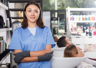 Obraz premium Girl hairdresser in gloves standing in salon, clients on background