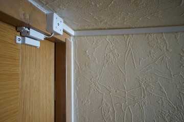magnetically pinned white color close-up detector mounted on a wooden brown door