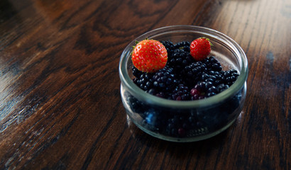 Glass bowl with blackberries and strawberries.