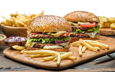 Hamburgers and French fries on the wooden tray.