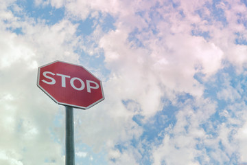 Road sign STOP with light cloudy sky in background.