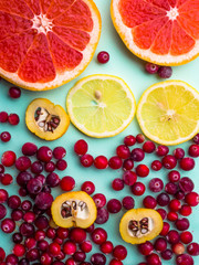 beautiful fresh sliced mixed citrus fruits as background with red cranberries, cydonia on blue background, concept of healthy eating, dieting, top view