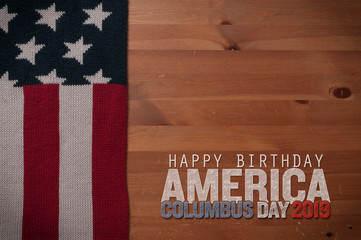 Fototapeta na wymiar Stars and stripes scarf on a wooden table and an inscription for the Columbus Day celebrations. Columbus day 2019.