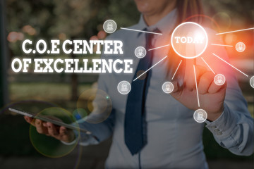 Writing note showing Coe Center Of Excellence. Business concept for being alpha leader in your position Achieve Woman wear formal work suit presenting presentation using smart device