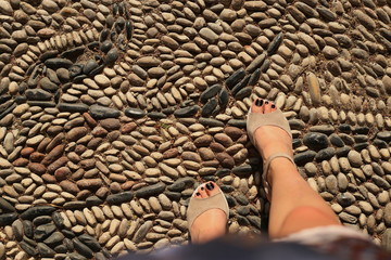 woman legs sidewalk small patterned sea pebbles